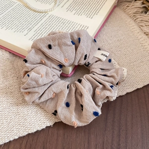 Detail of beige scrunchie with blue embroidery and white lace on an vintage book