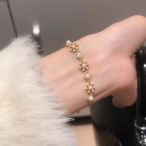 Detaillierte Ansicht des verstellbaren Perlenblumen-Armbands in Gold am Handgelenk