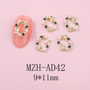 Détail de bijoux d'ongles en forme de couronne de Noël avec strass émeraudes et perles