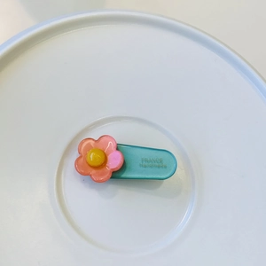 Sweet mint green floral hair clip with pink flower on a white ceramic display tray