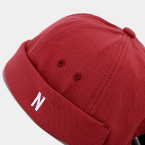 Macro shot of red cotton miki hat with white embroidered N letter and textured canvas fabric