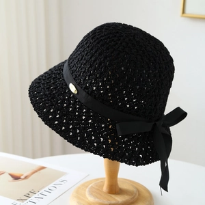 Détail d'un chapeau cloche en crochet noir avec ruban gros-grain et plaque logo dorée