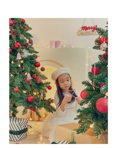 Detail of a white winter dress and beige beret worn by a child in a cozy Christmas setting