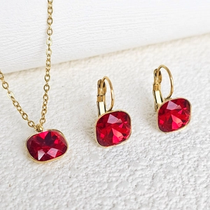 Close-up of gold stainless steel necklace and earrings set with red square crystals