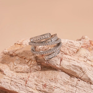 Crossed multi-layer silver ring with geometric zircon stones on a natural rock