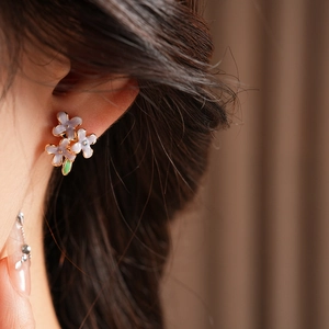Details von eleganten lila Emaille-Blumenohrringen mit Vergoldung an einem Modell