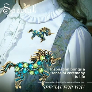 Close-up of vintage horse brooches with teal crystals pinned on a white blouse