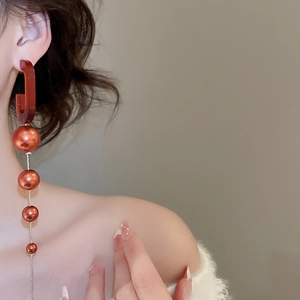 Detail of vintage red tassel earrings with gradient pearls on an Asian model