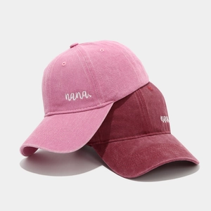 Detail of pink and burgundy cotton baseball caps featuring white nana embroidery details