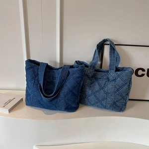 Sac fourre-tout en denim bleu foncé et moyen avec surpiqûres en losanges sur socle blanc