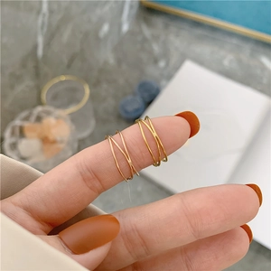 Detail shot of triple-layered interwoven gold rings on hand showing sleek metal texture
