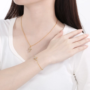 Close-up of gold cross pendant necklace and bracelet set with sparkling crystals