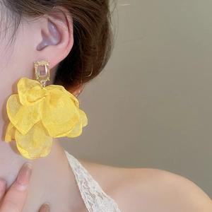 Detail of yellow fabric flower earrings featuring layered petals and a clear zircon stud