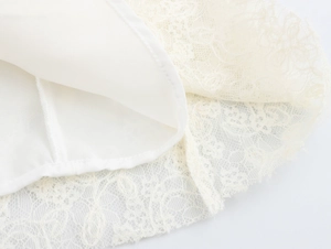 Detailed close-up of white lace fabric texture and inner lining on a long dress