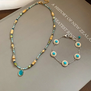 Bohemian beaded necklace and bracelet set with oval cat eye stone pendant on a book