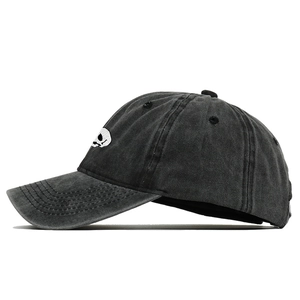 Detailed close-up of a skull embroidery on a washed black cotton baseball cap
