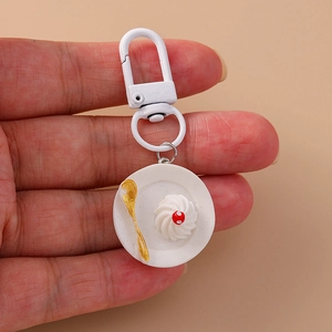 Close-up of creative faux food keychain featuring a cream dessert on a mini plate
