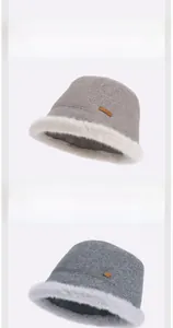 Detail of warm winter bucket hat with grey wool fabric, cream faux fur trim and leather label