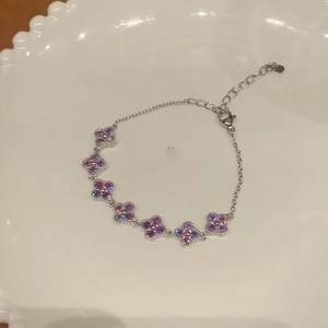 Detail of silver flower chain bracelet with seven purple clover charms and zircon accents