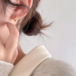 Detailed view of minimalist gold cross stud earrings worn on the earlobe for a chic look
