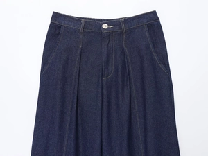 Detailed view of high-waisted dark blue denim pants with yellow contrast stitching