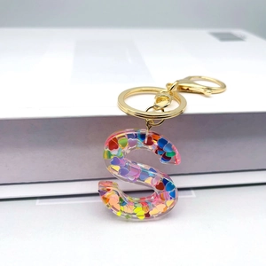Detail of letter S keychain with colorful heart sequins inside resin and gold clasp