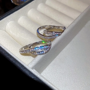 Close-up of silver U-shaped earrings with zircons and starburst light effect in a jewelry box