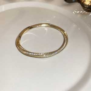 Macro detail of 18K gold plated bangle featuring a twisted pavé setting with sparkling zircons