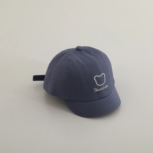 Détail d'une casquette bébé en coton bleu avec une jolie broderie de petit ours