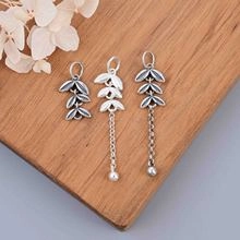 Macro detail of S925 sterling silver leaf pendants and tassel charms on wood