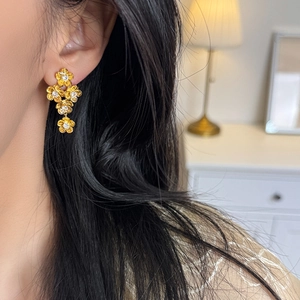 Elegant gold floral drop earrings with sparkling zircon crystals worn by a model