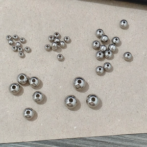 Detailed macro view showing various sizes of polished stainless steel beads with through-holes