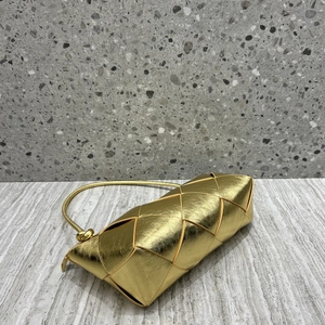 Close-up of golden woven leather texture and knot detail on a luxury crossbody bag