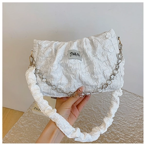 Detail of white pleated shoulder bag with silver chain and textile brand label