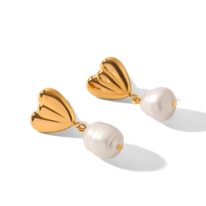 Gros plan de boucles d'oreilles cœur dorées avec perles baroques blanches irrégulières
