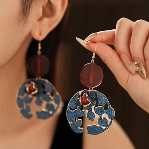 Detail of vintage flower and leaf drop earrings with red resin and hollow gold metal