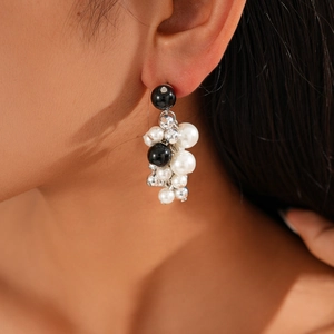 Close-up of dangling black and white pearl beaded earrings on a model's ear