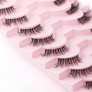 Close-up of dense black half false eyelashes arranged neatly in a pink tray