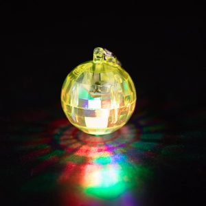 Glow of yellow disco ball keychain with colorful light reflections on dark background