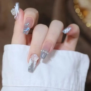 Detail of grey gradient press-on nails featuring 3D embossed roses and glitter accents