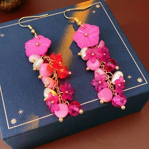 Gros plan sur boucles d'oreilles fleur rose avec perles et cristaux sur boîte bleue