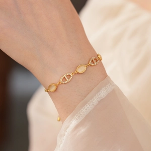 Gros plan d'un bracelet doré avec opale ovale et pavé de zircons sur le poignet