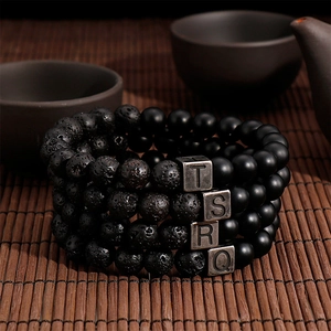 Detailed macro view of four black volcanic lava and agate stone letter beaded bracelets