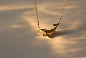 Detailed view of matte 18K gold plated whale pendant necklace with refined texture