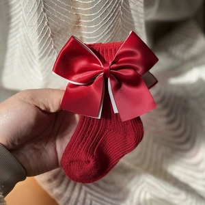 Festive red baby knit socks with large satin bow for Christmas and New Year celebrations