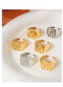 Detail view of gold and silver open rings with hammered texture in a ceramic tray