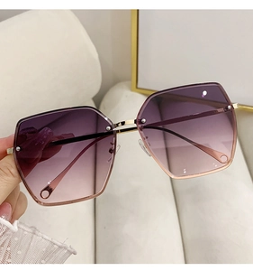 Detail of oversized rimless sunglasses with purple gradient lenses and gold metal arms