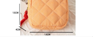 Detail of orange checkered quilted makeup bag showing 13cm x 4cm compact dimensions