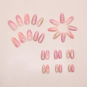 Detailed view of pink almond press-on nails with gold foil, stars, and pearl accents