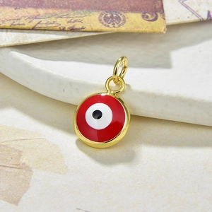 Macro shot of red Evil Eye pendant in gold finish on decorative ceramic dish